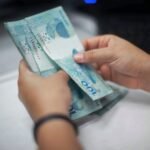 Mãos contando notas de 100 reais, representando pagamento