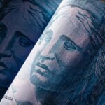 Close em detalhes da nota de 100 reais, mostrando a efígie da República em tom azul.