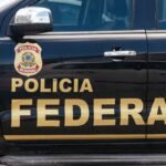 Viatura da Polícia Federal com identificação oficial e brasão da PF em destaque na porta do veículo, usada em operação de investigação.